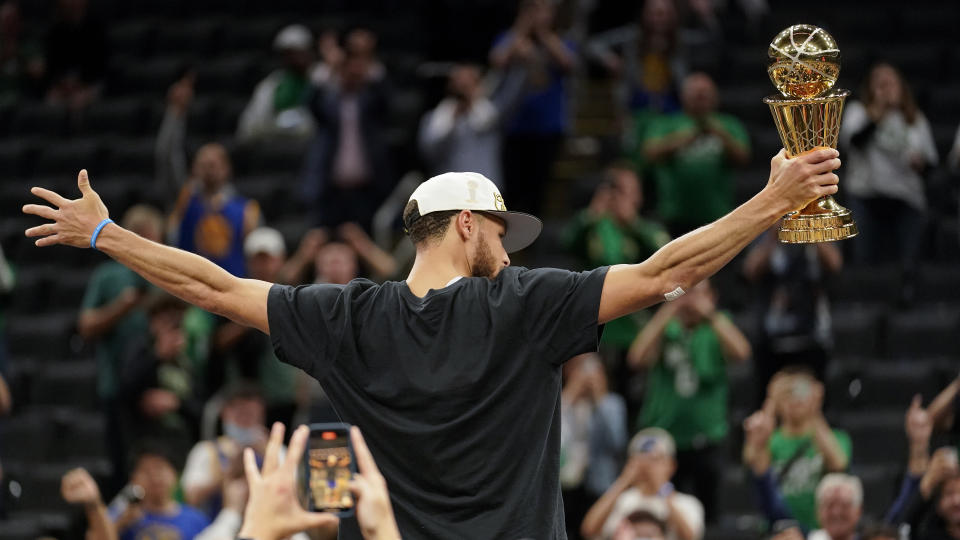 Golden State Warriors guard Stephen Curry celebrates with the Bill Russell Trophy for most valuable player after the Warriors defeated the Boston Celtics in Game 6 to win basketball's NBA Finals, Thursday, June 16, 2022, in Boston. (AP Photo/Steven Senne)