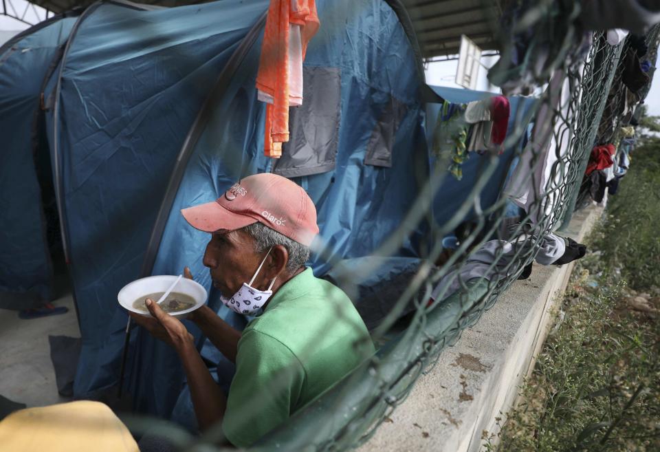 A Venezuelan sheltering at a community center gets a meal in Arauquita, Colombia, Thursday, March 25, 2021, on the border with Venezuela. Thousands of Venezuelans are seeking shelter in Colombia this week following clashes between Venezuela's military and a Colombian armed group in a community along the nations' shared border. (AP Photo/Fernando Vergara)