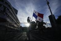 A demonstrator throws hold a Panamanian national flag on a fence during a protest against a recently approved mining contract between the government and Canadian mining company First Quantum, outside the National Assembly in Panama City, Monday, Oct. 23, 2023. (AP Photo/Arnulfo Franco)