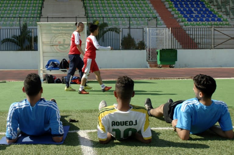 Fatiha Belkadi and Faiza Messaouar of 'Afak Relizane' walk past male palyers ahead of their training session in the Algerian city of Relizane