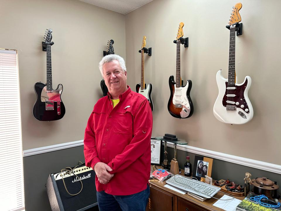 Don Carlton is shown in his office, where items from his guitar collection hang on the wall.