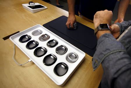 Customer Peter Watling (R) is assisted by a staff member of the Sydney Apple store as he tries on an Apple Watch after it went on display April 10, 2015. REUTERS/David Gray