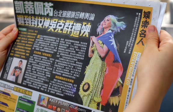 In this photo illustration taken on April 30, 2015, a local resident reads a newspaper showing US singer Katy Perry wearing Taiwan's national flag in Taipei. The intricacies of the "one China" policy may not have been uppermost on her mind, but US pop star Katy Perry caused a stir in Asia this week with her politically-charged choice of dress at a Taipei concert.  AFP PHOTO / Sam Yeh        (Photo credit should read SAM YEH/AFP/Getty Images)