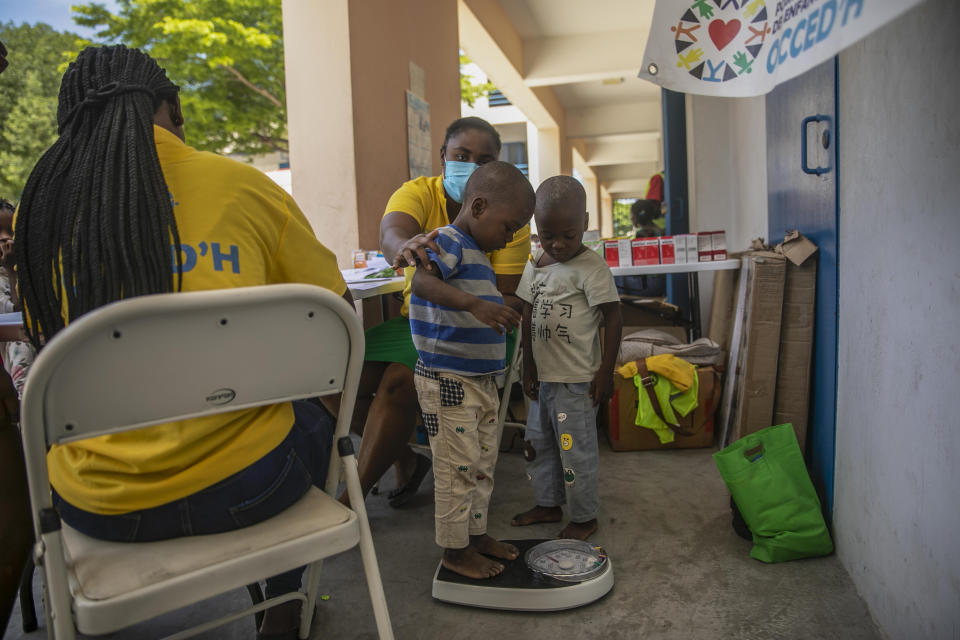 Workers of the NGO known by the acronym OCCED'H weigh a child forced to leave his home in Cite Soleil due to clashes between armed gangs, at a school turned into a makeshift shelter in Port-au-Prince, Haiti, Saturday, July 23, 2022. (AP Photo/Odelyn Joseph)