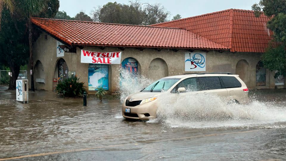 A vehicle drives through water on a flooded street in Ventura, California. - Eugene Garcia/AP