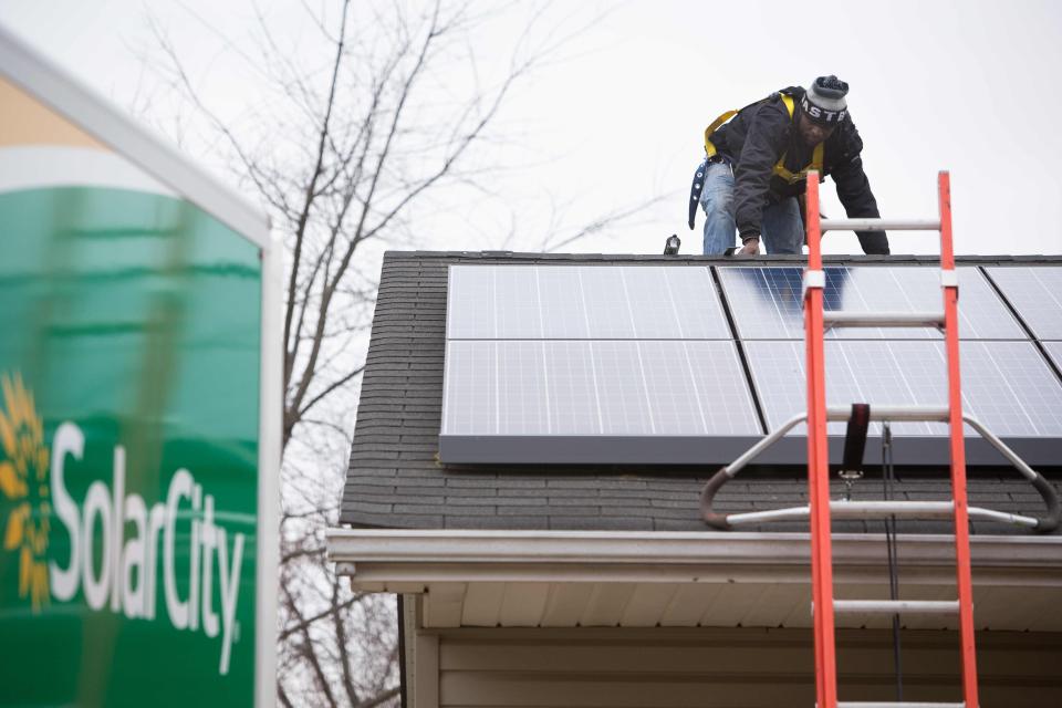 Maxwell Nyoni with SolarCity installs solar panels at a home in Bear.