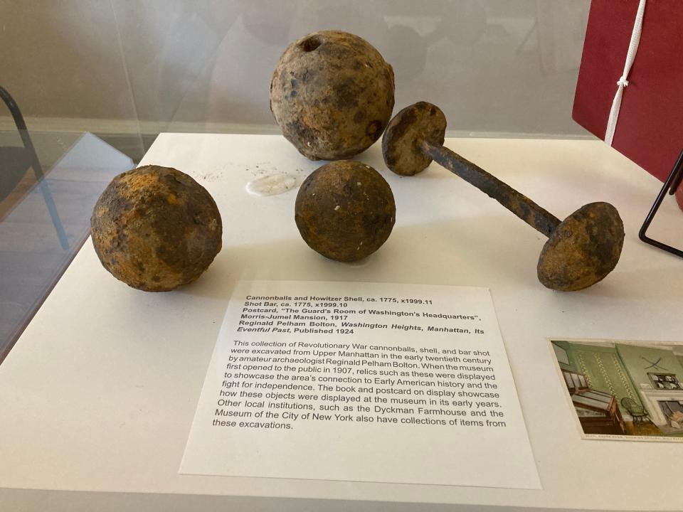 Revolutionary War cannonballs on display in a glass case at the Morris-Jumel Mansion.