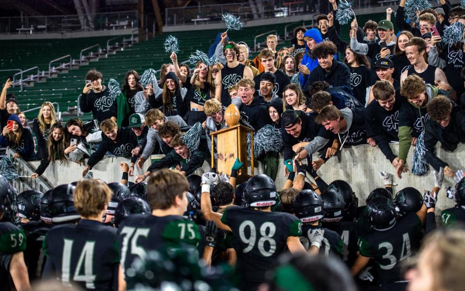 Fossil Ridge football players and students celebrate with the Harmony Cup after beating rival Fort Collins during the Canvas Community Classic at Canvas Stadium on Saturday, Sept. 30, 2022.