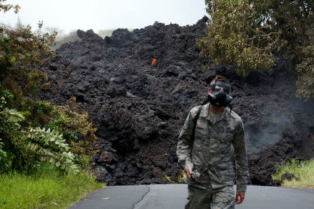 Senior Airman John Linzmeier, of the Hawaii National Guard, walks away from a lava flow on Highway 137 southeast of Pahoa during ongoing eruptions of the Kilauea Volcano in Hawaii, U.S., May 20, 2018. REUTERS/Terray Sylvester