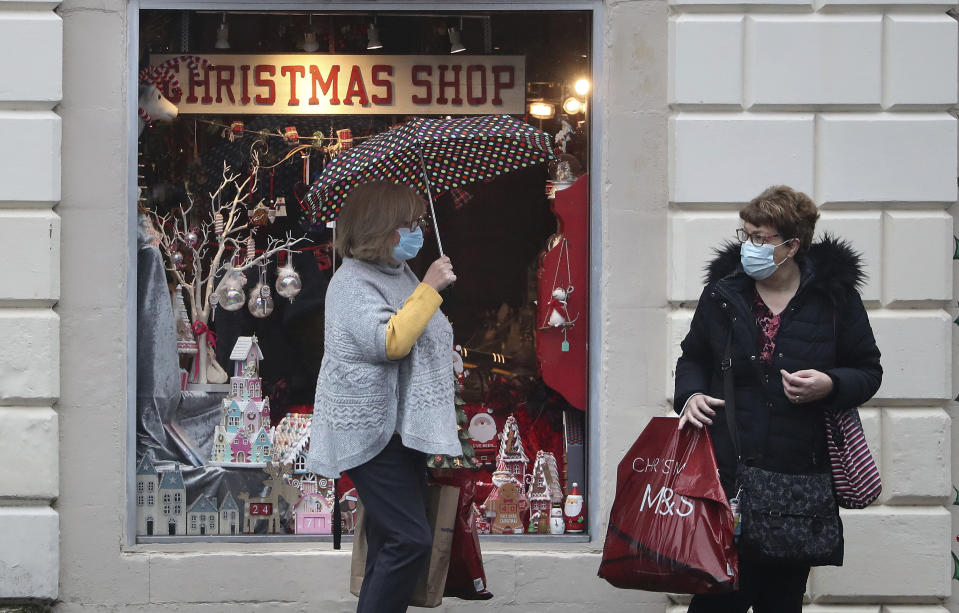 People wearing face coverings outside a Christmas Shop in Stirling, Scotland, Friday Nov. 20, 2020. This shop will close later Friday along with other non-essential shops, bars, restaurants, hairdressers and visitor attractions whilst schools remain open, due to the latest government restrictions imposed to slow the spread of coronavirus. (Andrew Milligan/PA via AP)