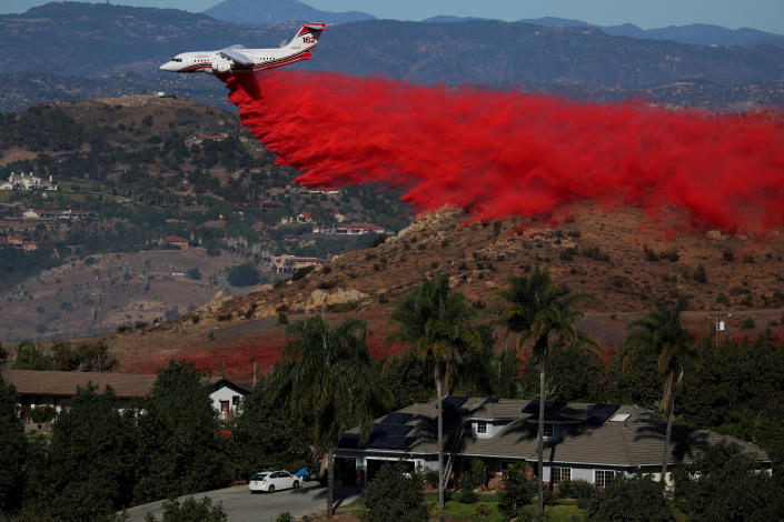 <p>An aircraft drops fire retardant as firefighters take advantage of light winds to attack the Lilac Fire, a fast moving wild fire in Bonsall, Calif., Dec. 8, 2017. (Photo: Mike Blake/Reuters) </p>
