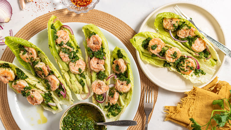 Two plates with shrimp lettuce wraps and chimichurri sauce