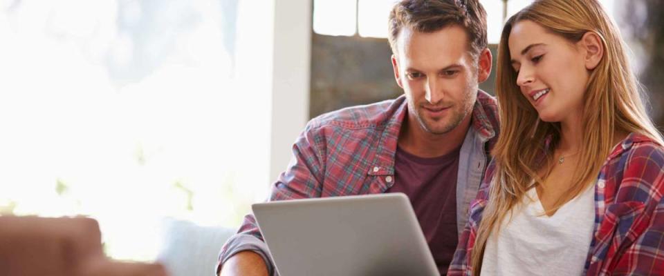 Couple At Home In Lounge Using Laptop Computer