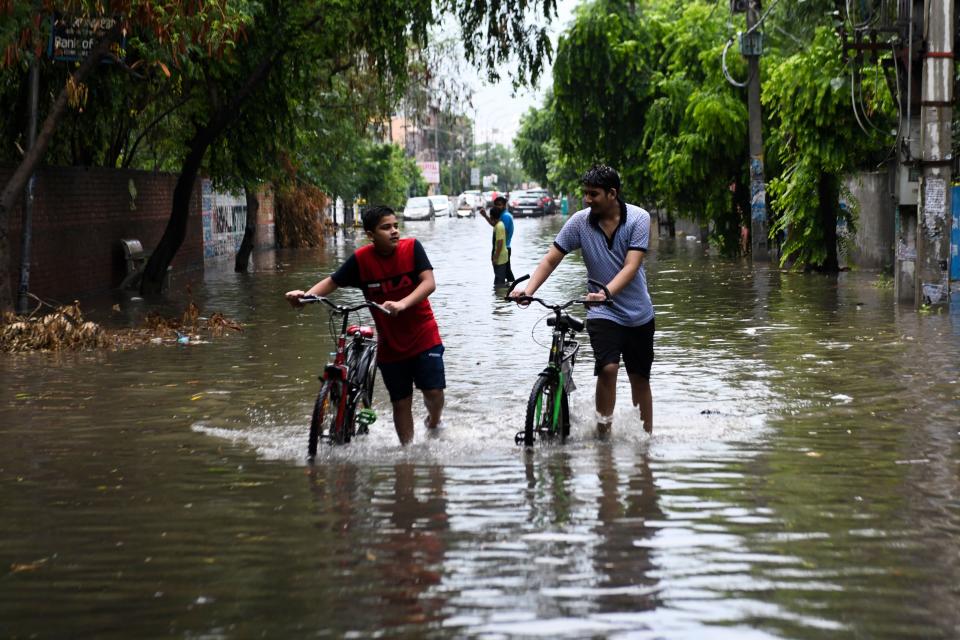 Youths push thir bicycles along a water-logged street following heavy rains in Amritsar on July 19, 2020. (Photo by NARINDER NANU / AFP) (Photo by NARINDER NANU/AFP via Getty Images)