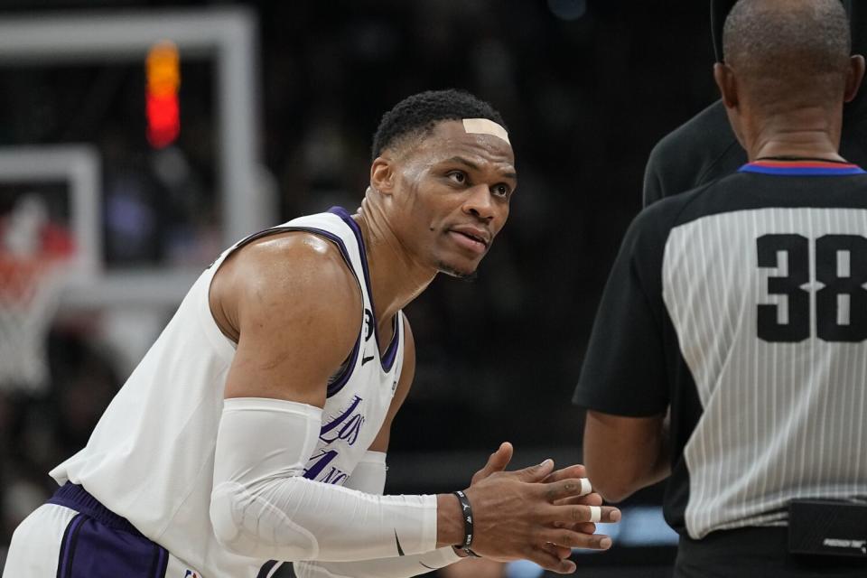 Lakers guard Russell Westbrook, wearing a bandage on his forehead after an injury, talks with an official Nov. 26, 2022.