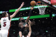 Boston Celtics guard Jaylen Brown, center, drives to the basket against Miami Heat forward Nikola Jovic (5) and guard Tyler Herro during the first half of Game 5 of an NBA basketball first-round playoff series, Wednesday, May 1, 2024, in Boston. (AP Photo/Charles Krupa)