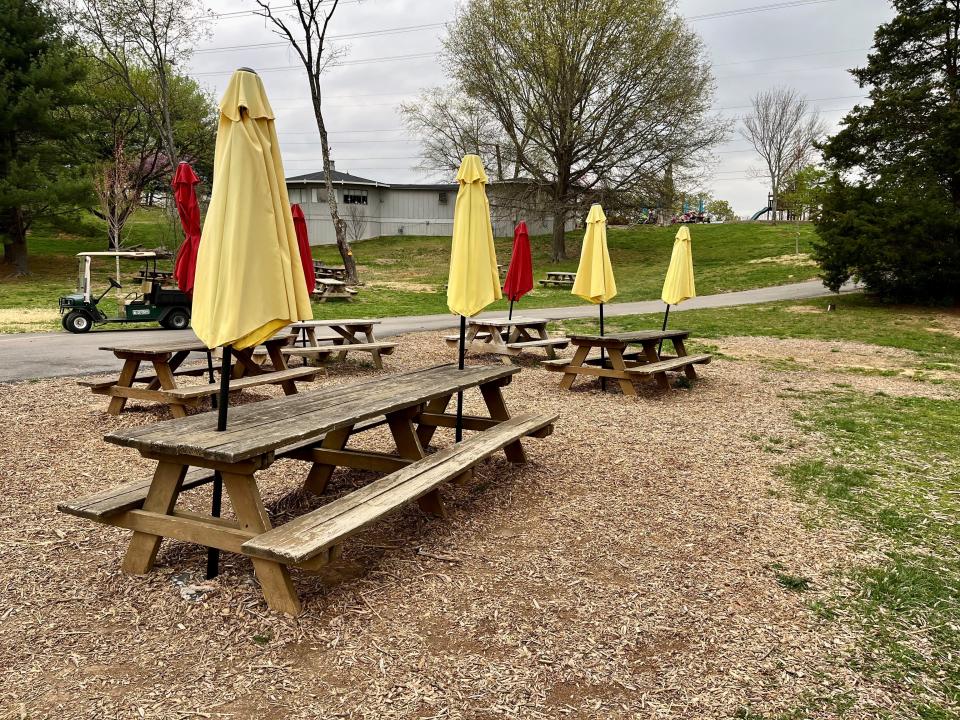 Some picnic tables at Tate’s School sit near where a big pine tree and some other trees were damaged in a tornado last August.