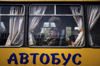 Women wait in a bus at a center for displaced people in Zaporizhzhia, Ukraine, Monday, May 2, 2022. The sign reads: "Bus." (AP Photo/Evgeniy Maloletka)