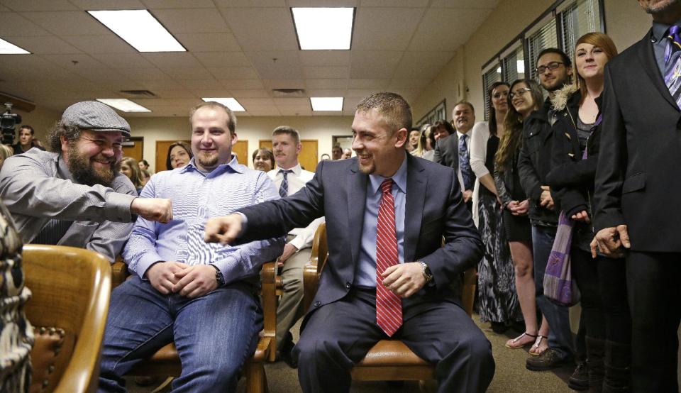 Sean Green, seated right, is congratulated by Sean Fitzgerald, left, as Scott O'neil looks on before Green is issued his new Washington state legal marijuana license Wednesday, March 5, 2014, in Olympia, Wash. Green, a medical marijuana dispensary operator from Spokane, was issued the producer-processor license under the state's recreational pot law at the Liquor Control Board meeting. (AP Photo/Elaine Thompson)