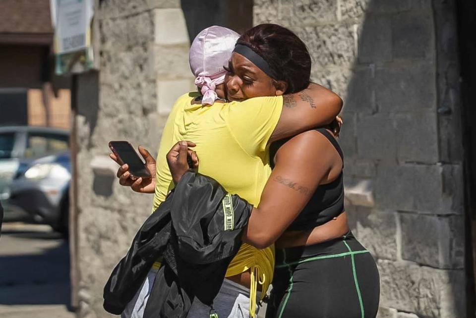 A woman  receives a hug from a supporter outside the scene of a shooting outside a home in Chicago, Tuesday, June 15, 2021.  Police say an argument at a house on Chicago's South Side erupted in fatal gunfire, leaving some dead and others injured.