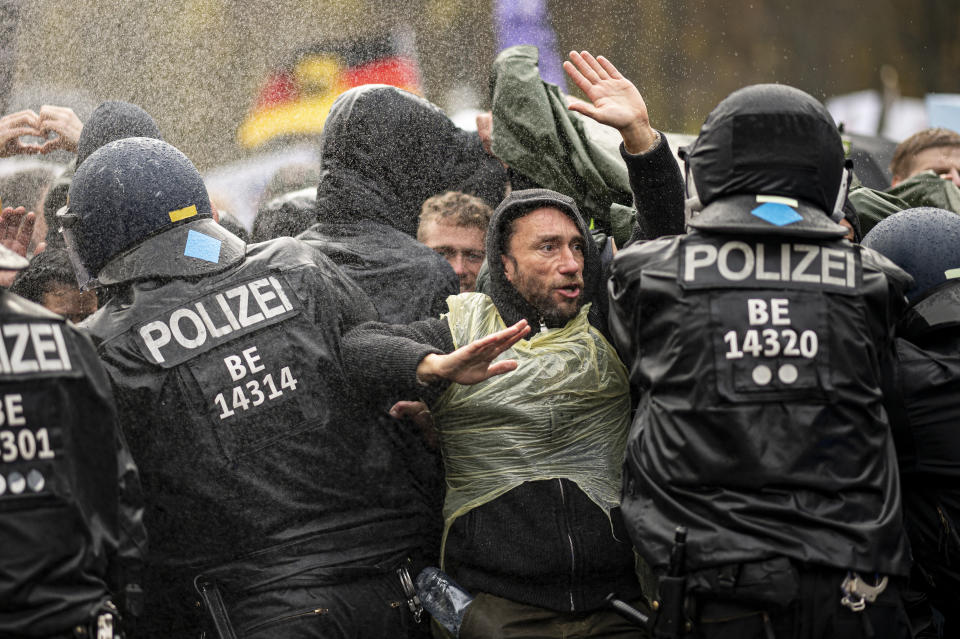 Police officers try to push back protesters on a blocked a road between the Brandenburg Gate and the Reichstag building, home of the German federal parliament, as people attend a protest rally in front of the Brandenburg Gate in Berlin, Germany, Wednesday, Nov. 18, 2020 against the coronavirus restrictions in Germany. Police in Berlin have requested thousands of reinforcements from other parts of Germany to cope with planned protests by people opposed to coronavirus restrictions. (Fabian Sommer/dpa via AP)