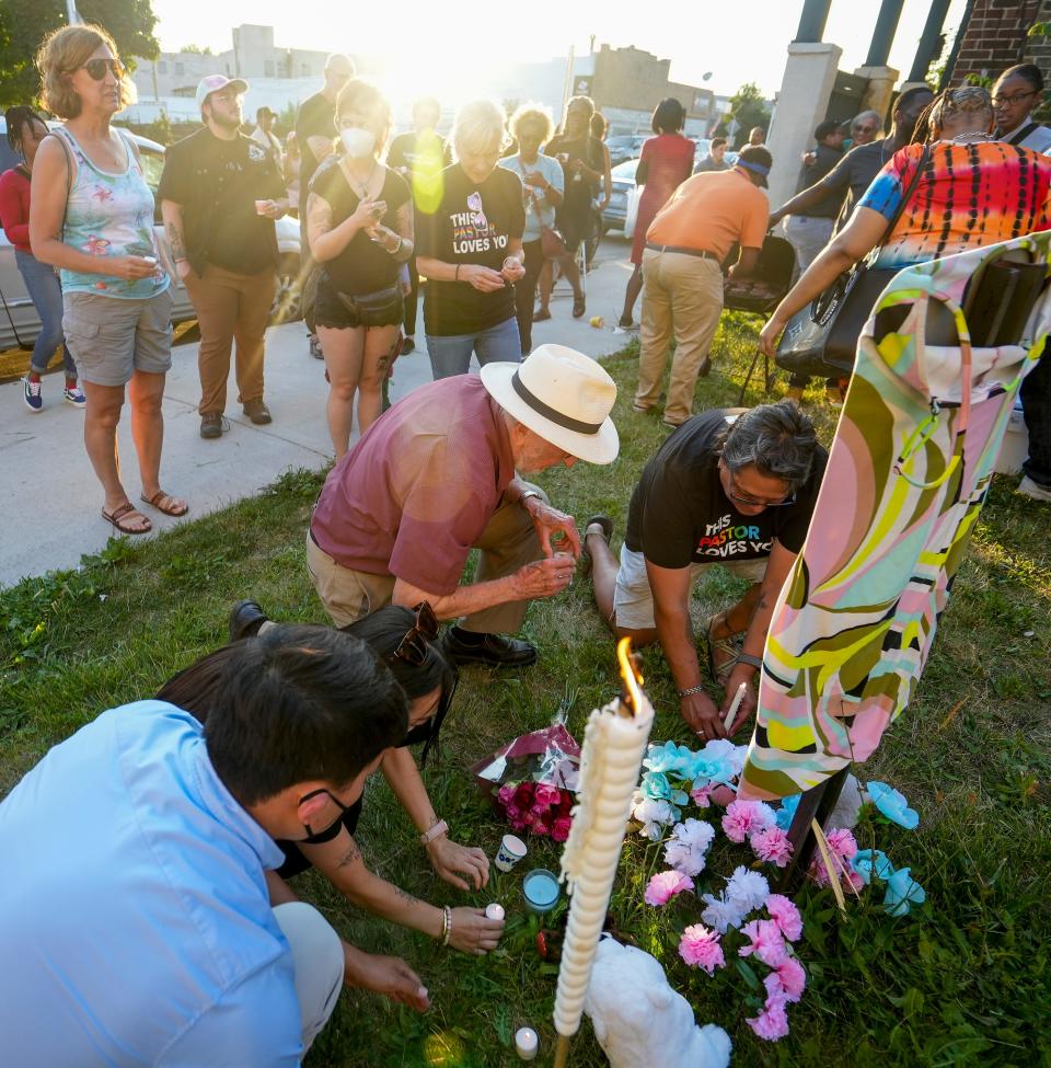 Joseph Ellwanger, in the hat kneeling, and Char Guiliani, far right kneeling, light candles to remember Brazil Johnson, a transgender woman who was fatally shot on June 15.