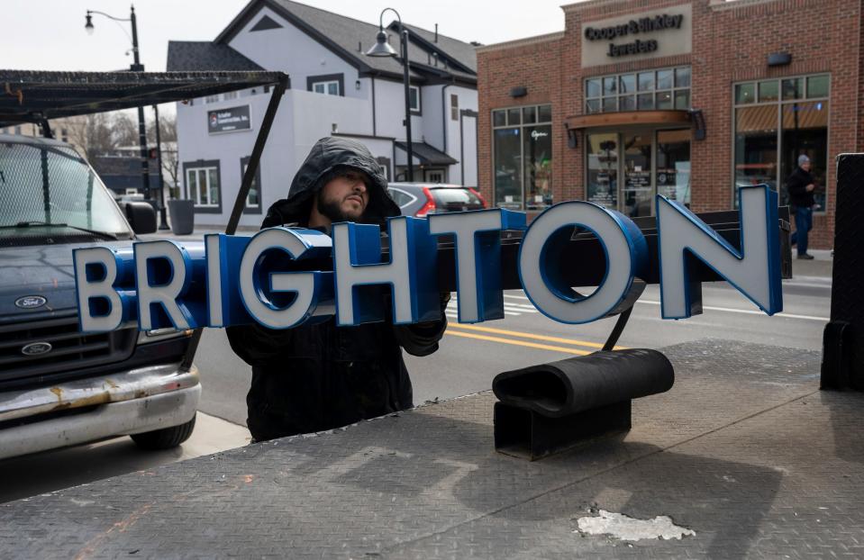 Charlie John, of 4 Tech Signs, works to install a new sign at the Brighton Yoga Center in Brighton on Tuesday, March 19, 2024.