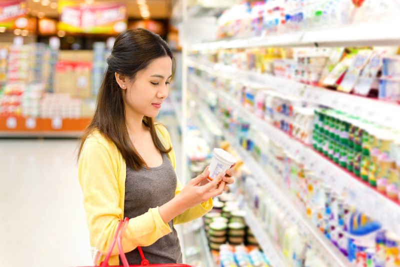 Asian Lady Looking at Yogurt in Supermarket