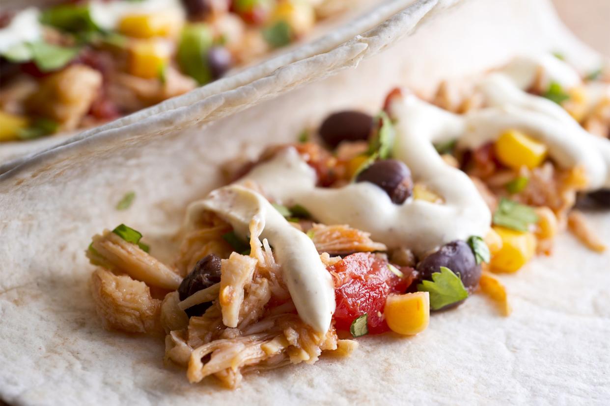 Closeup of one shredded chicken taco (tinga de pollo) with another blurred in the background