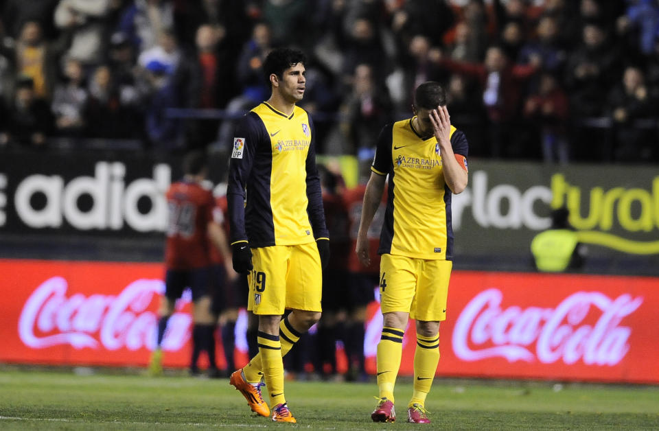 Osasuna's teammates celebrate their second goal, backgound, as Atletico de Madrid's Diego Costa of Brazil, left, and Gabi, walk away, during their Spanish League soccer match, at El Sadar stadium in Pamplona, Spain, Sunday, Feb. 23, 2014. (AP Photo/Alvaro Barrientos)