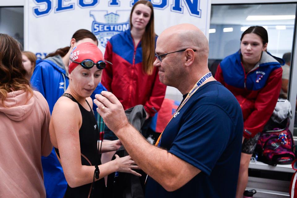 Fairport head coach Mike Kennedy shows Kaleigh Lawrence her time after the final of the 50 yard freestyle during the NYSPHSAA Girls Swimming & Diving Championships, Saturday, Nov. 18, 2023.