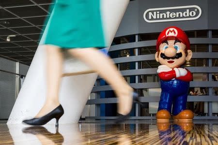 A woman walks past a figure of "Mario", a character in Nintendo's "Mario Bros." video games, at a Nintendo centre in Tokyo July 29, 2015. REUTERS/Thomas Peter