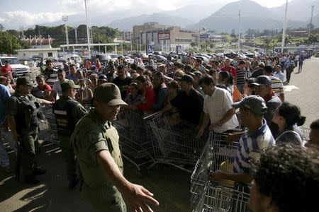 National guards control the entrance of a private supermarket as people line up to enter in San Cristobal January 15, 2015. REUTERS/Carlos Eduardo Ramirez