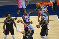 Miami Heat guard Kendrick Nunn (25) goes up for a shot past Minnesota Timberwolves guard Anthony Edwards (1), center Karl-Anthony Towns (32) and forward Josh Okogie (20) during the first half of an NBA basketball game Friday, April 16, 2021, in Minneapolis. (AP Photo/Craig Lassig)