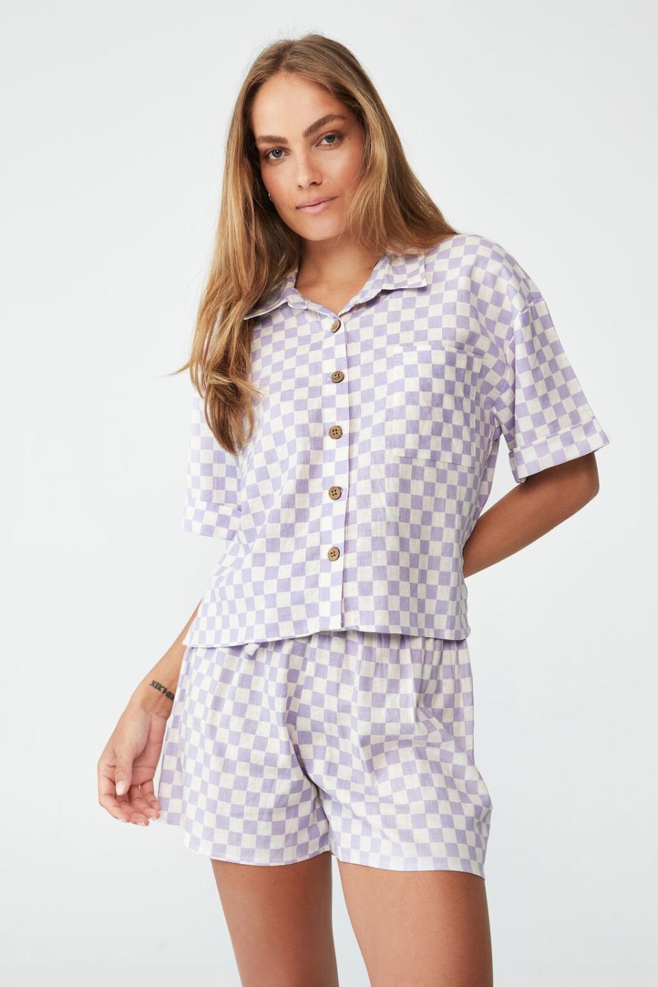Girl with long hair stands in check short pyjamas