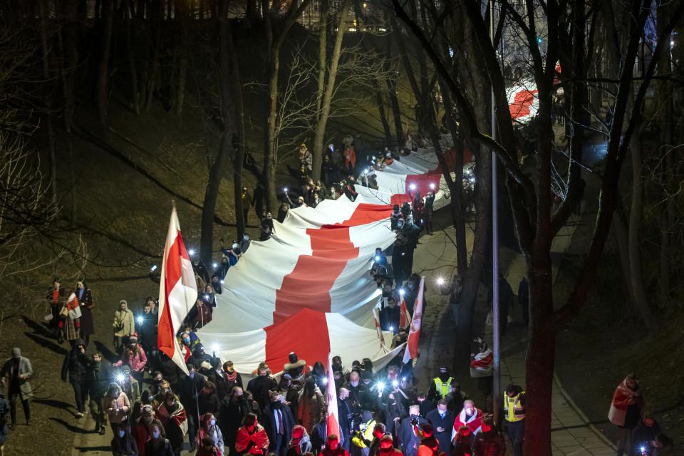 People carry a giant historical flag of Belarus during a celebration 103rd anniversary of the declaration of the Belarusian People's Respublic, in Vilnius, Lithuania, Thursday, March 25, 2021. Freedom Day is an unofficial holiday in Belarus celebrated on 25 March to commemorate the declaration of independence by the Belarusian Democratic Republic on that date in 1918.(AP Photo/Mindaugas Kulbis)