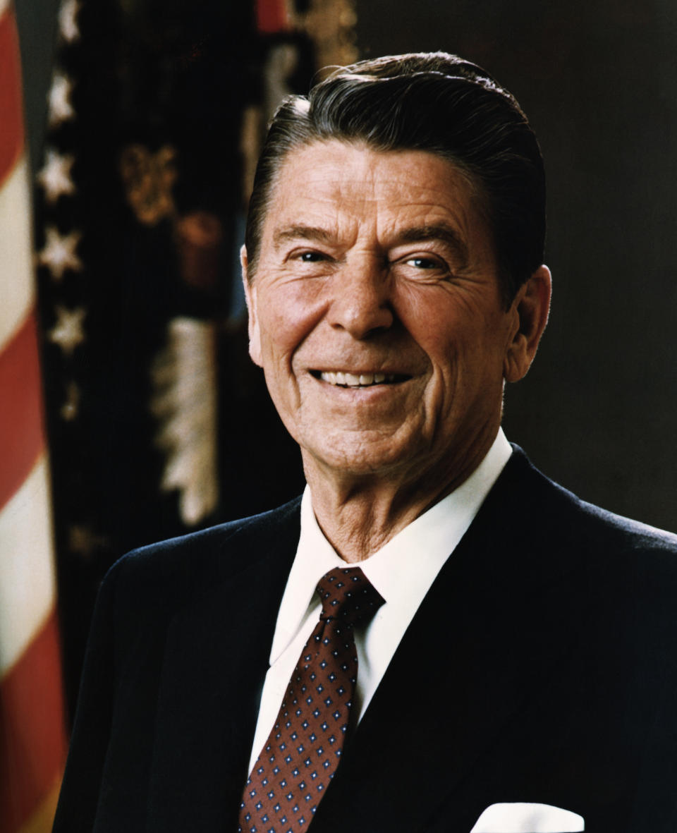 Man in a suit posing in front of an American flag