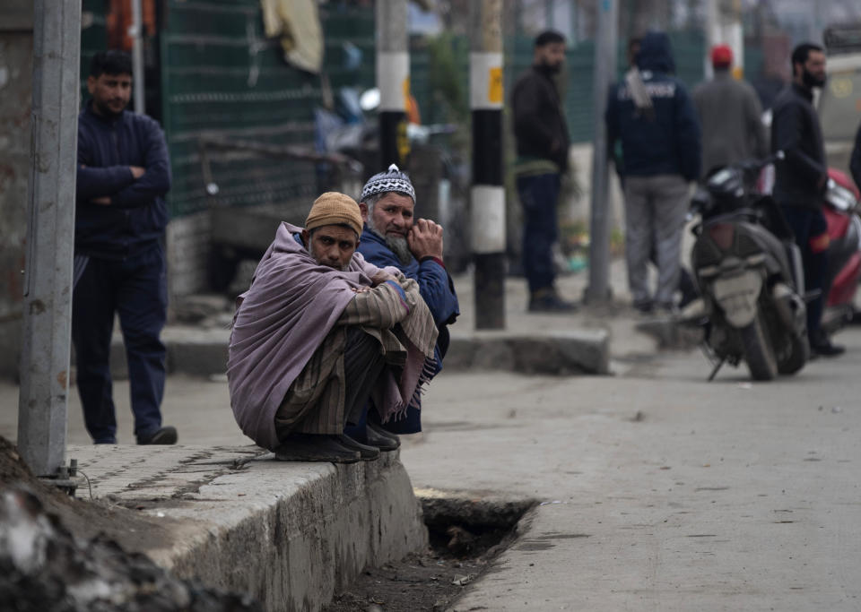 Elderly Kashmiri men rest on a pavement outside a taxi stand in Srinagar, Indian controlled Kashmir, Tuesday, Feb. 9, 2021. Businesses and shops have closed in many parts of Indian-controlled Kashmir to mark the eighth anniversary of the secret execution of a Kashmiri man in New Delhi. Hundreds of armed police and paramilitary soldiers in riot gear patrolled as most residents stayed indoors in the disputed region's main city of Srinagar. (AP Photo/Mukhtar Khan)