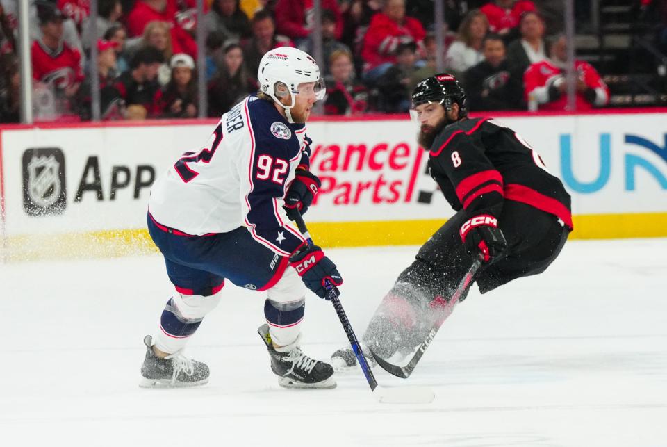 Apr 7, 2024; Raleigh, North Carolina, USA; Columbus Blue Jackets left wing Alexander Nylander (92) holds onto the puck against Carolina Hurricanes defenseman Brent Burns (8) during the first period at PNC Arena. Mandatory Credit: James Guillory-USA TODAY Sports