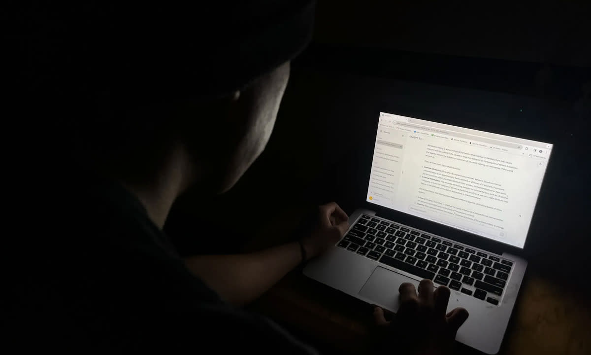 This is a photo of someone typing on a Macbook in the dark.