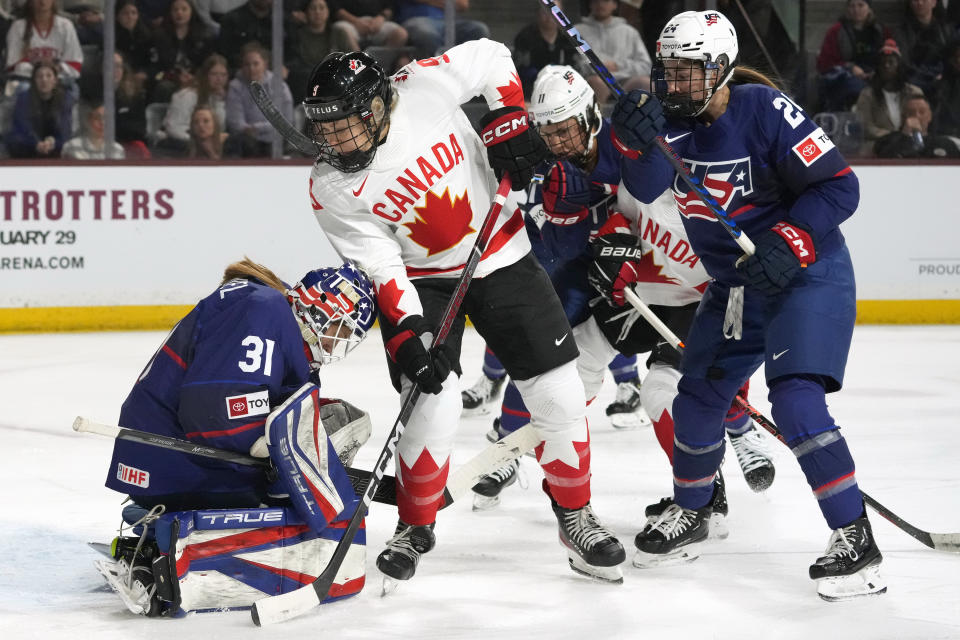 United States goaltender Aerin Frankel (31) makes a save on a shot by Canada forward Jessie Eldridge (9) as United States defender Natalie Buchbinder (24) and United States forward Abby Roque (11) look on during the first period of a rivalry series women's hockey game Wednesday, Nov. 8, 2023, in Tempe, Ariz. (AP Photo/Ross D. Franklin)