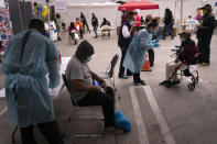 FILE - In this Feb. 10, 2021, file photo, Viola Roberson, 75, far right, and 61-year-old Mark McNamee, foreground, wait for their COVID-19 vaccine at a vaccination site set up in the parking lot of the Los Angeles Mission in the Skid Row area of Los Angeles. While older homeless adults were eligible for vaccination in many states earlier this year, the shots now are finally reaching thousands of younger adults who are homeless. (AP Photo/Jae C. Hong, File)