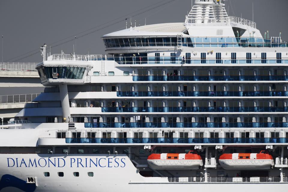 Passengers stand on balconies on the Diamond Princess cruise ship, with around 3,600 people quarantined onboard due to fears of the new coronavirus, at the Daikoku Pier Cruise Terminal in Yokohama port on February 10, 2020. - Around 60 more people on board the quarantined Diamond Princess cruise ship moored off Japan have been diagnosed with novel coronavirus, the country's national broadcaster said on February 10, raising the number of infected passengers and crew to around 130. (Photo by CHARLY TRIBALLEAU / AFP) (Photo by CHARLY TRIBALLEAU/AFP via Getty Images)