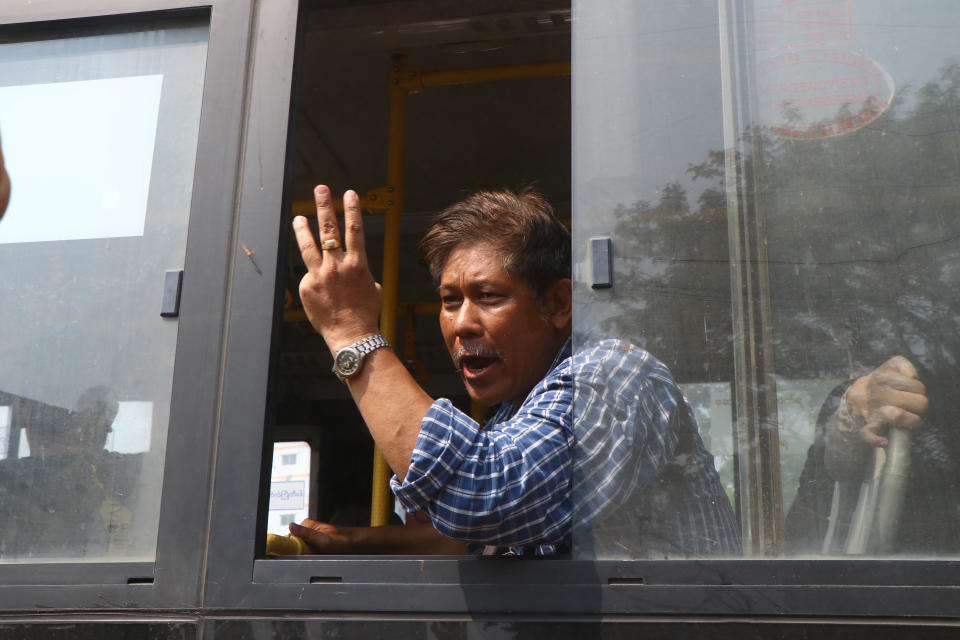 An arrested protester flashes the three-fingered salute while onboard a bus that is getting out of Insein prison and will transport them to an undisclosed location Wednesday, March 24, 2021 in Yangon, Myanmar. (AP Photo)