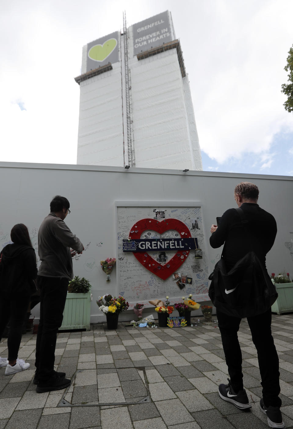 People mourn at the Grenfell tower to mark the two-year anniversary of the Grenfell Tower block fire in London, Friday, June 14, 2019. Survivors, neighbors and politicians including London Mayor Sadiq Khan attended a church service of remembrance on Friday for the Grenfell Tower blaze, the deadliest fire on British soil since World War II. (AP Photo/Frank Augstein)