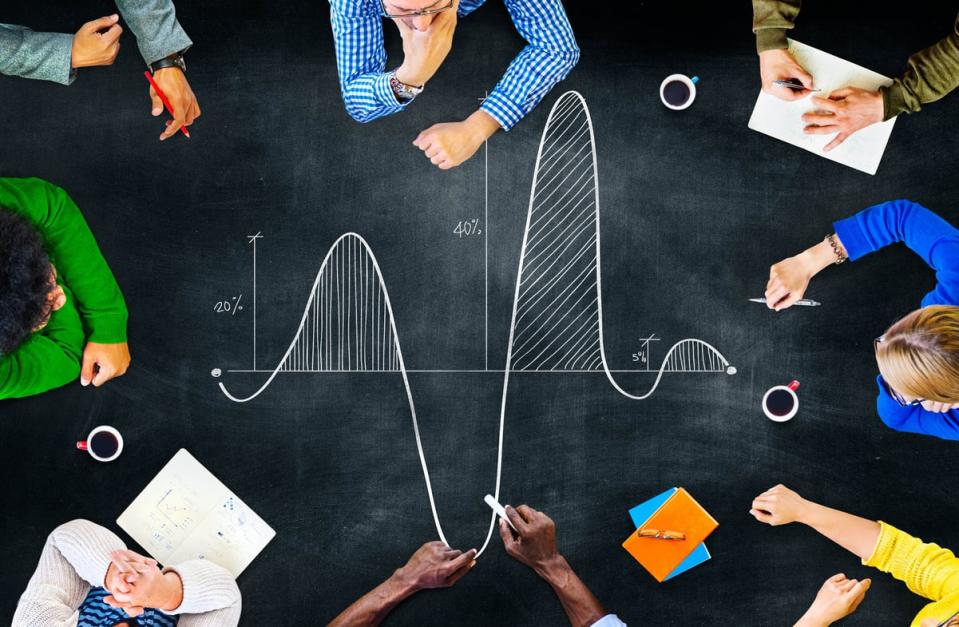 A group of people looking at a parabola and math equations written in chalk on a table.