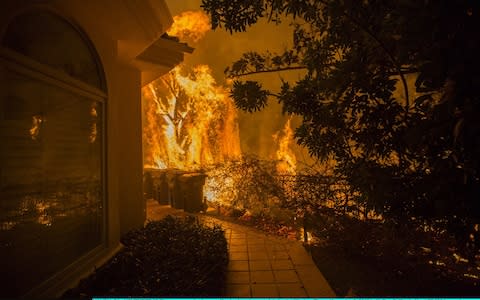Flames approach a house with a loud roaring sound during the Woolsey Fire - Credit: Getty