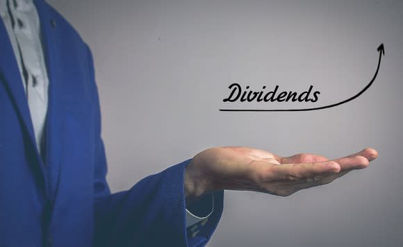 Man's hand, palm up, with an upward arrow and the word dividends above it.