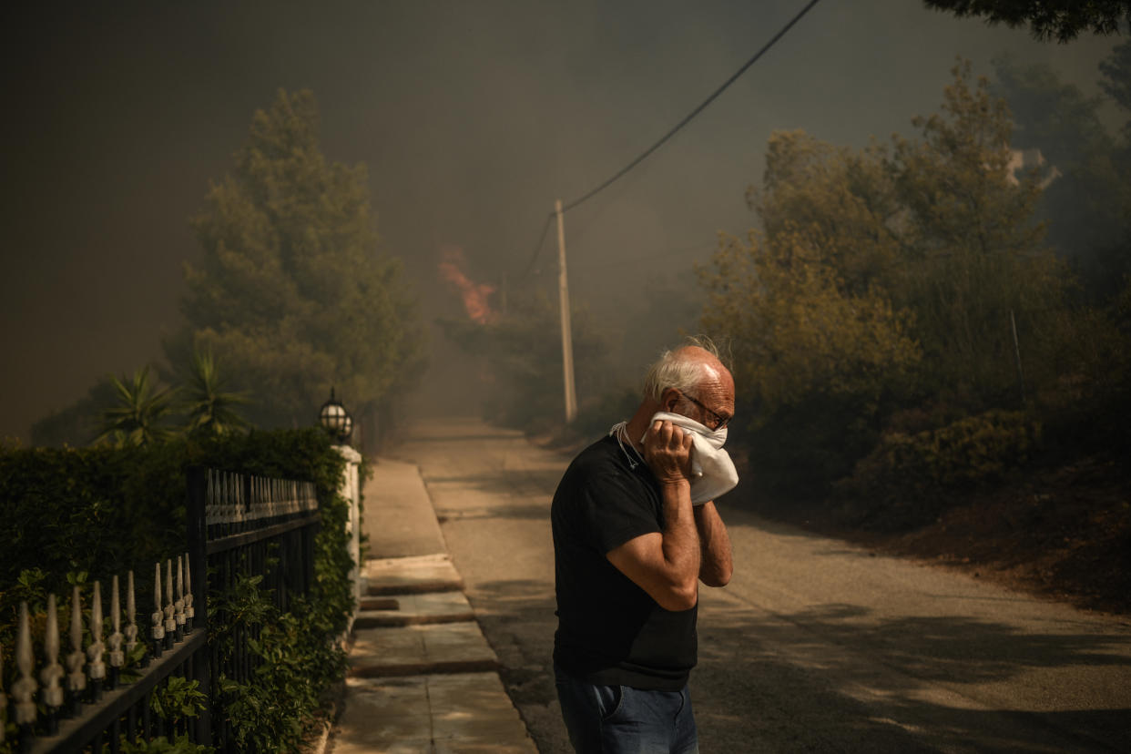 A local resident covers his face during a wildfire in Dion, Greece, on Monday. 