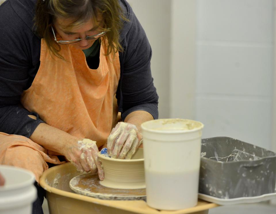 Heather Pilchard sits at a pottery wheel as she creates a bowl.
